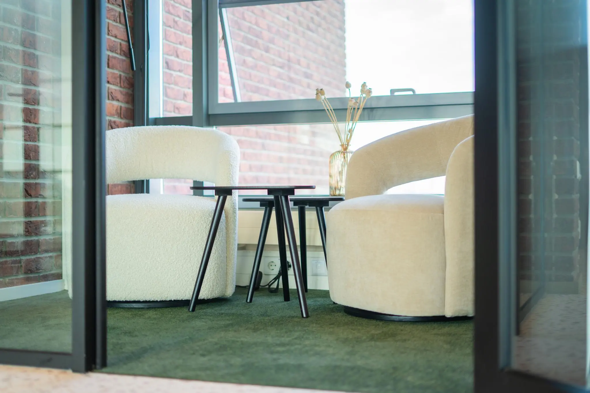 Twee moderne fauteuils met ronde vormen en een set zwarte bijzettafels in een zithoek aan de Joop Geesinkweg.